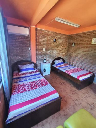 two beds in a room with a brick wall at Departamento 1er Piso-Costa del Potiy in Encarnación