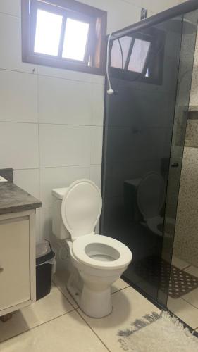 a bathroom with a white toilet and a shower at Apartamento 03 - Refúgio do Descanso in São Francisco do Sul