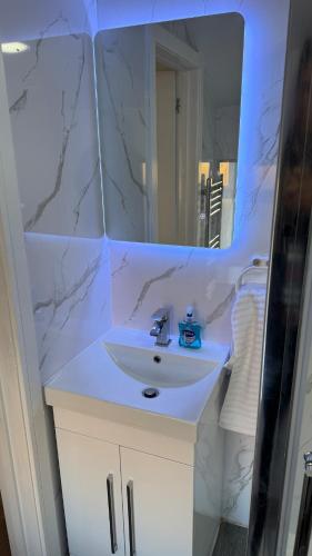 a bathroom with a white sink and a mirror at Aurang House, 1 Bedroom, with Kitchen, 55" Flat TV, Private Parking in Huddersfield