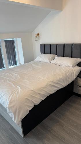 a large bed with white sheets and pillows at Aurang House, 1 Bedroom, with Kitchen, 55" Flat TV, Private Parking in Huddersfield