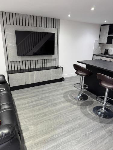 a room with a fireplace and two bar stools at Aurang House, 1 Bedroom, with Kitchen, 55" Flat TV, Private Parking in Huddersfield