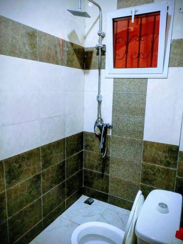 a bathroom with a toilet and a window at Villa Julien 2 chambres in Rufisque