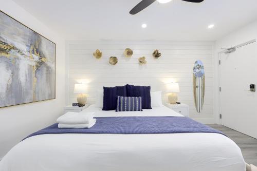a white bedroom with a large bed with blue pillows at Siesta Key Beach Resort and Suites in Sarasota