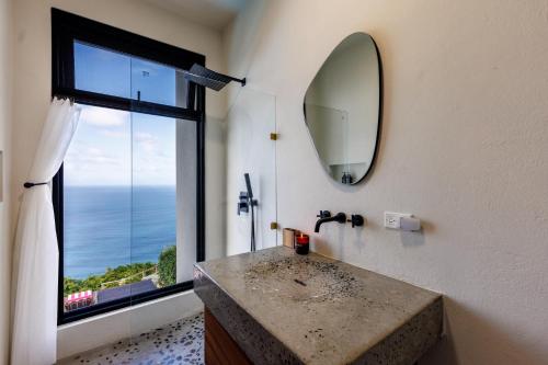 a bathroom with a sink with a mirror and a window at Villa Odyssea BVI in Tortola Island
