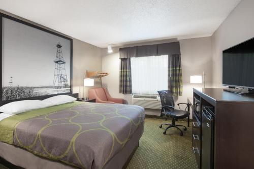 a hotel room with a bed and a flat screen tv at Super 8 by Wyndham Bedford DFW Airport West in Bedford