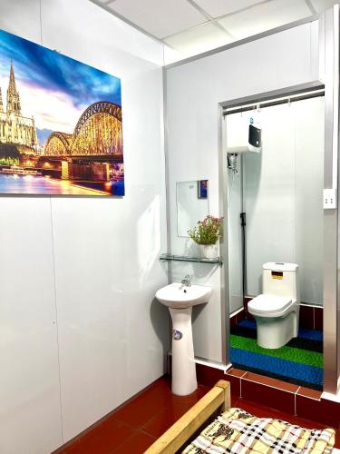 a bathroom with a toilet and a picture of a bridge at LaMera Homestay in Ben Tre