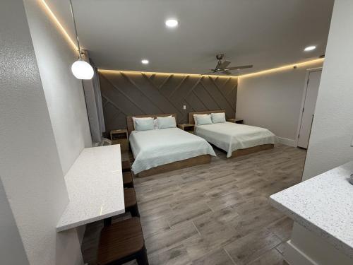 two beds in a small room with wooden floors at Renovated Beachfront Studio, New Kitchen, Pool in Daytona Beach