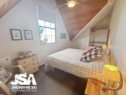 a attic bedroom with a bed and a window at Lakeside Chalet in Jindabyne