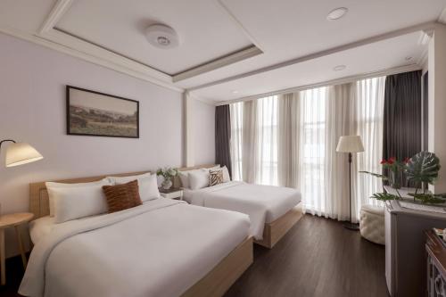a hotel room with two beds and a window at Quy Hung Hotel And Spa Central in Ho Chi Minh City