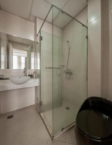 a bathroom with a glass shower and a sink at Quy Hung Hotel And Spa Central in Ho Chi Minh City