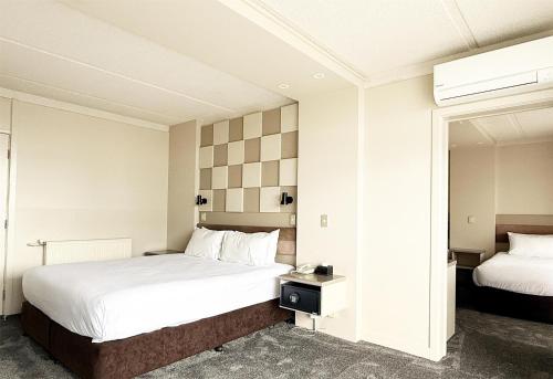 a hotel room with two beds and a mirror at Sudima Hotel Lake Rotorua in Rotorua