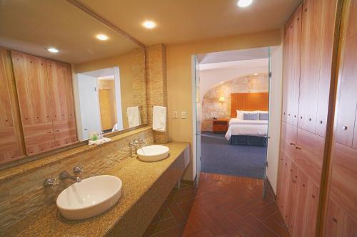 a bathroom with two sinks and a bedroom at Hotel Flamingo Inn in Querétaro