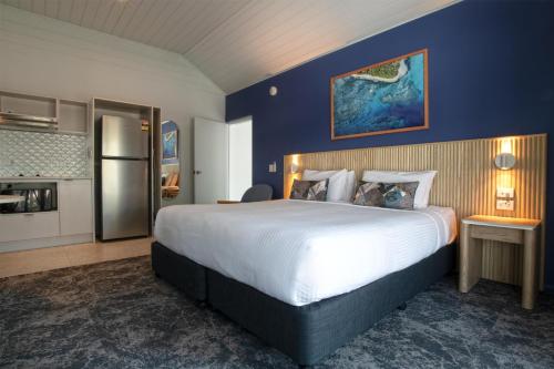 a hotel room with a large bed and a refrigerator at Nightelier Mission Beach in Mission Beach