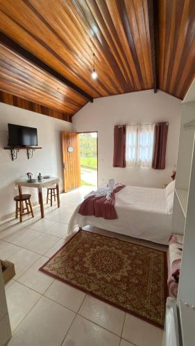 a bedroom with a large bed and a table at Estalagem Do Luar in Monte Verde