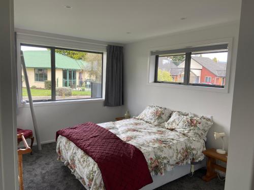 a bedroom with a bed and two windows at Red Tussock Motel in Te Anau