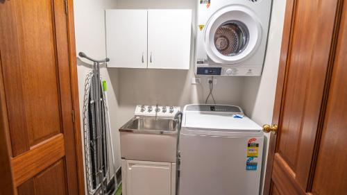 a small kitchen with a sink and a washing machine at Camelot in Dinner Plain