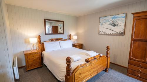 a bedroom with a large wooden bed with white sheets at Camelot in Dinner Plain