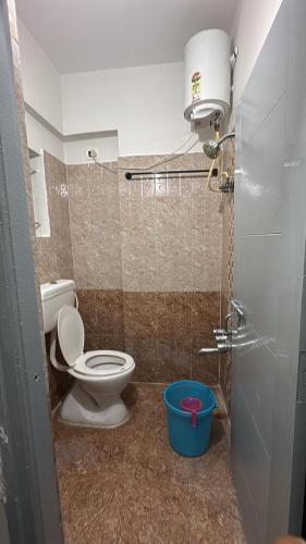 a bathroom with a toilet and a blue bucket at R Square Homes in Bangalore