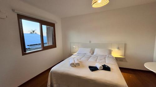 a bedroom with a bed with towels and a window at Casa da Praia Pousada in Torres