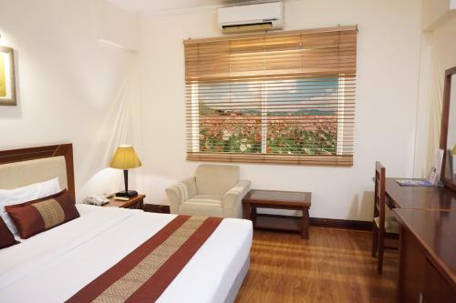 a bedroom with a bed and a chair and a window at Dong Khanh Hotel in Ho Chi Minh City