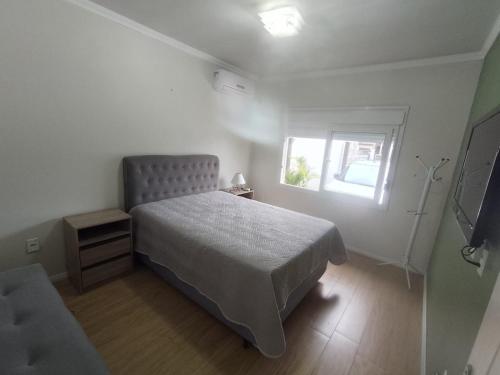 a small bedroom with a bed and a window at Casa aconchegante e completa em Osório - Ótima localização in Osório