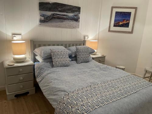 a bedroom with a bed with two night stands and two lamps at Braeburn in Bamburgh