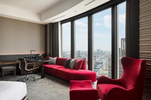 a living room with a red couch and chairs in front of windows at Conrad Osaka in Osaka