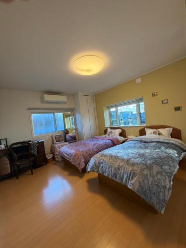 a bedroom with two beds and a chair and two windows at Sakura house in Kyoto