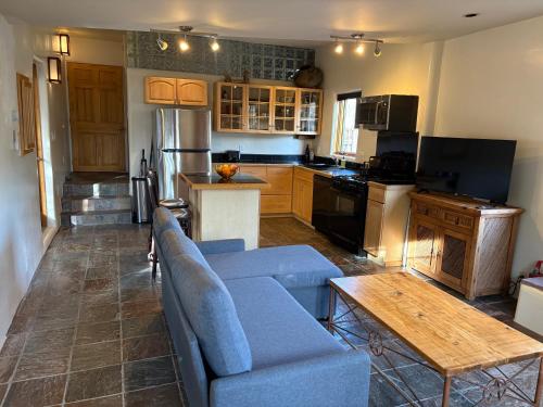 a living room with a blue couch and a kitchen at High Moon 4 Ten Thousand Waves Way in Santa Fe