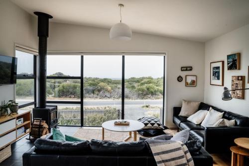 a living room with couches and a large window at Moonbird Beach Shack ~ Ocean Escape in Beaumaris Tasmania