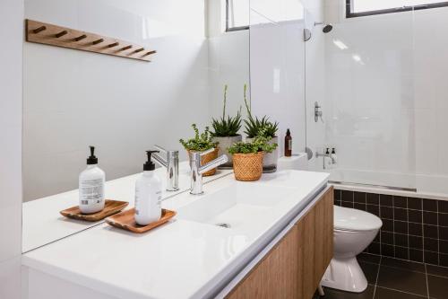 a white bathroom with a sink and a toilet at Moonbird Beach Shack ~ Ocean Escape in Beaumaris Tasmania