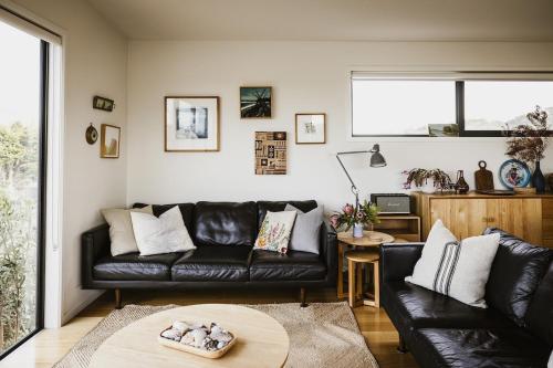 a living room with a black leather couch and a table at Moonbird Beach Shack ~ Ocean Escape in Beaumaris Tasmania