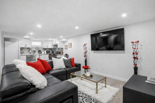 a living room with a black leather couch and red pillows at New 2BR Suite, Walk to Dining, Near Downtown in Calgary