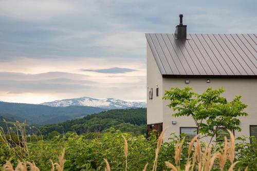 a house on a hill with mountains in the background at Villa HIGASHIKAWA -Hokkaido- in Higashikawa