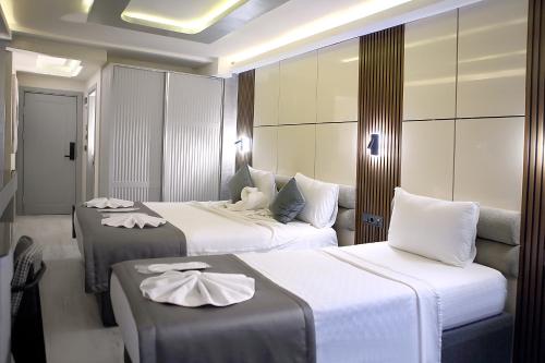 a hotel room with three beds with white sheets at AMARA OLD CITY HOTEL & Spa in Istanbul