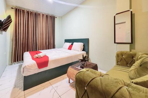 a hotel room with a bed and a couch at RedDoorz at Ingan Cio Homestay Berastagi in Berastagi