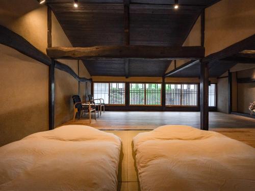 two beds in a room with a room with windows at 海野宿一棟貸し宿 上州屋 Unnojuku Joshuya in Tomi