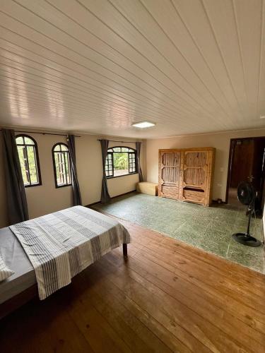 a large room with a bed and two windows at Sítio Castelo Branco - Morretes in Morretes