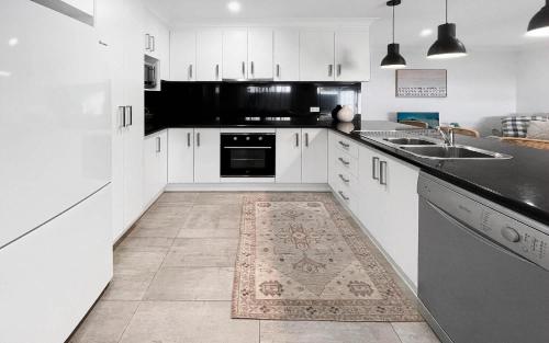 a kitchen with white cabinets and black counter tops at Oak Flats Escape in Oak Flats