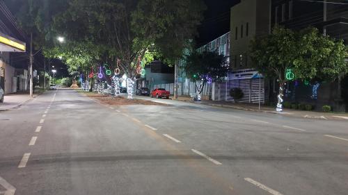 an empty street at night with trees and lights at Pousada Central in Montes Claros