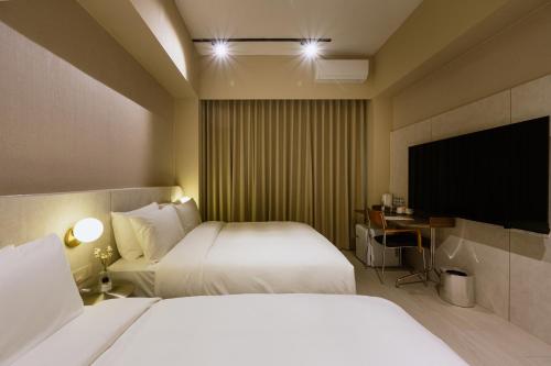 a hotel room with two beds and a flat screen tv at Mr Petter in Taichung