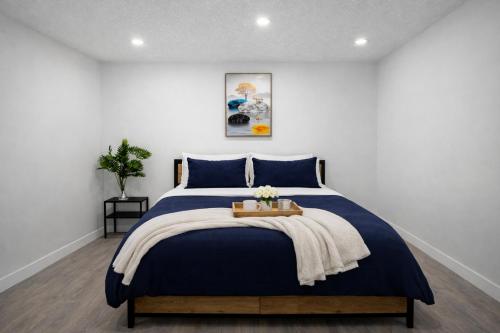 a bedroom with a bed with a blue bedspread at New 2BR Suite, Walk to Dining, Near Downtown in Calgary