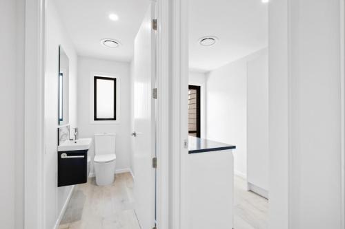 a white bathroom with a toilet and a sink at 44b Scarborough Terrace in Hanmer Springs