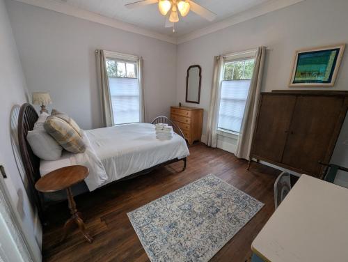 a bedroom with a bed and a table and two windows at Renovated Mill House in Historic Golden Belt in Durham