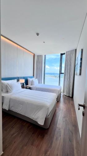 a hotel room with two beds and a large window at Executive Bay View A La Carte Hạ Long in Ha Long