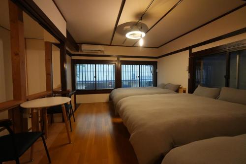 a room with three beds and a table and windows at TomaReno Beppu-Kitahama in Beppu