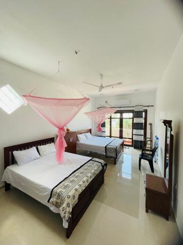 two beds in a bedroom with pink curtains at Hotel Meer in Ambalangoda
