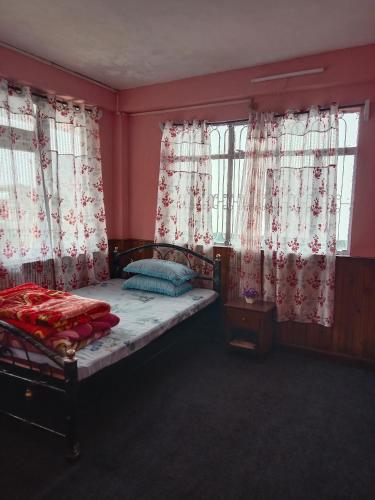 a bedroom with a bed with red walls and windows at Bluemoon stay in Darjeeling