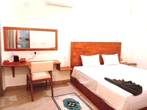 a bedroom with a bed and a desk and a mirror at Aureva Guest in Weligama
