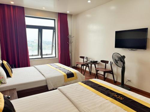 a hotel room with two beds and a flat screen tv at New Hotel Phủ Lý in Trượng Trâu
